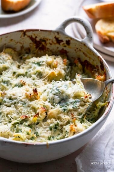 Photo of baked spinach artichoke dip in a white baking dish.