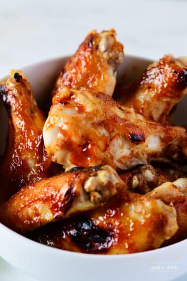 Photograph of bbq chicken wings in a white bowl.