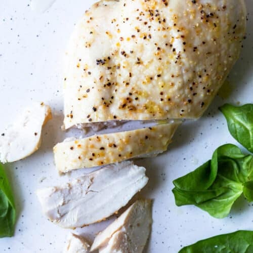 Photo of baked chicken breast on a white plate.