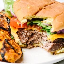 Hamburger with grilled sweet potatoes on a white plate.