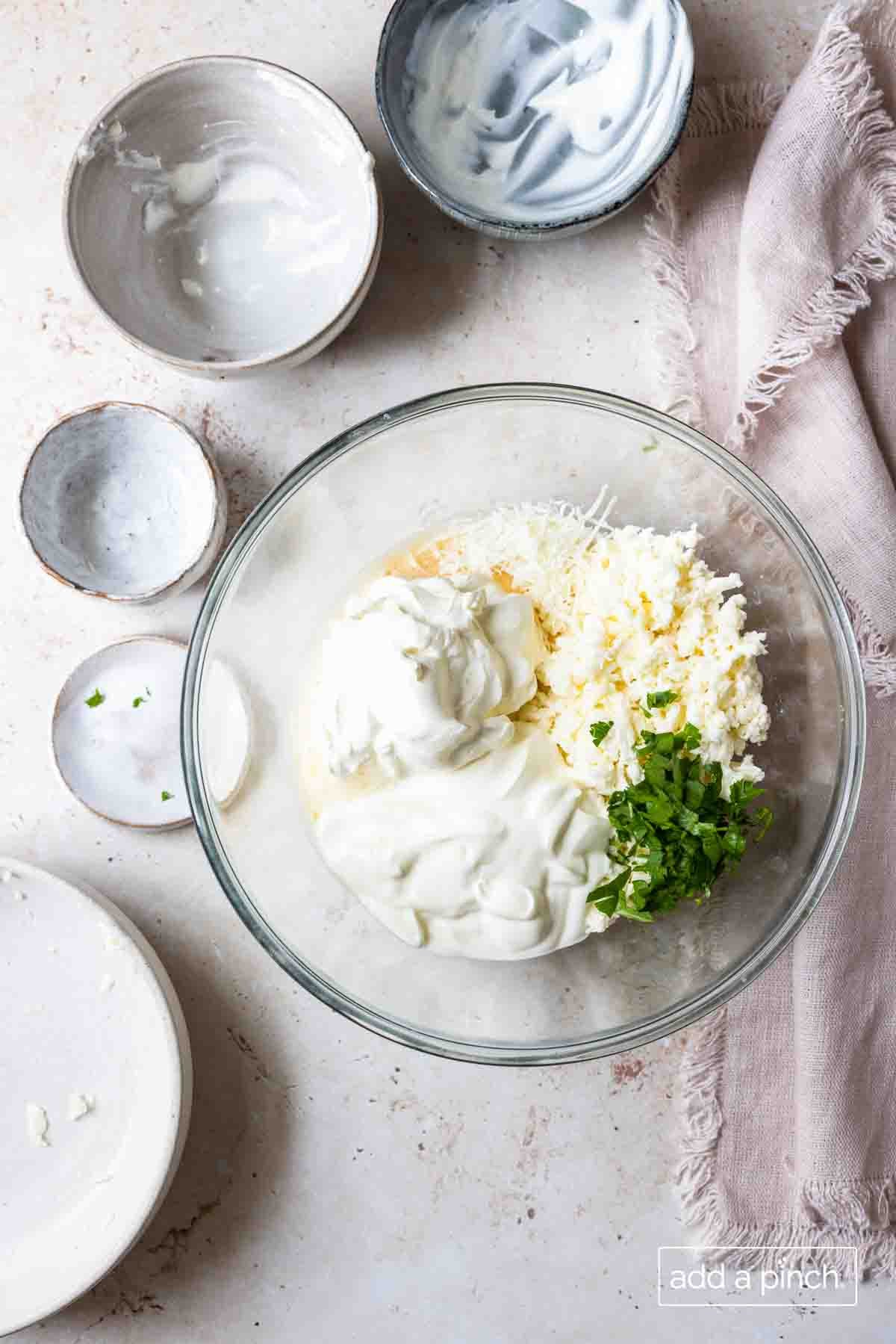 Image of ingredients for cheese filling used in lasagna recipe in a clear glass bowl. 