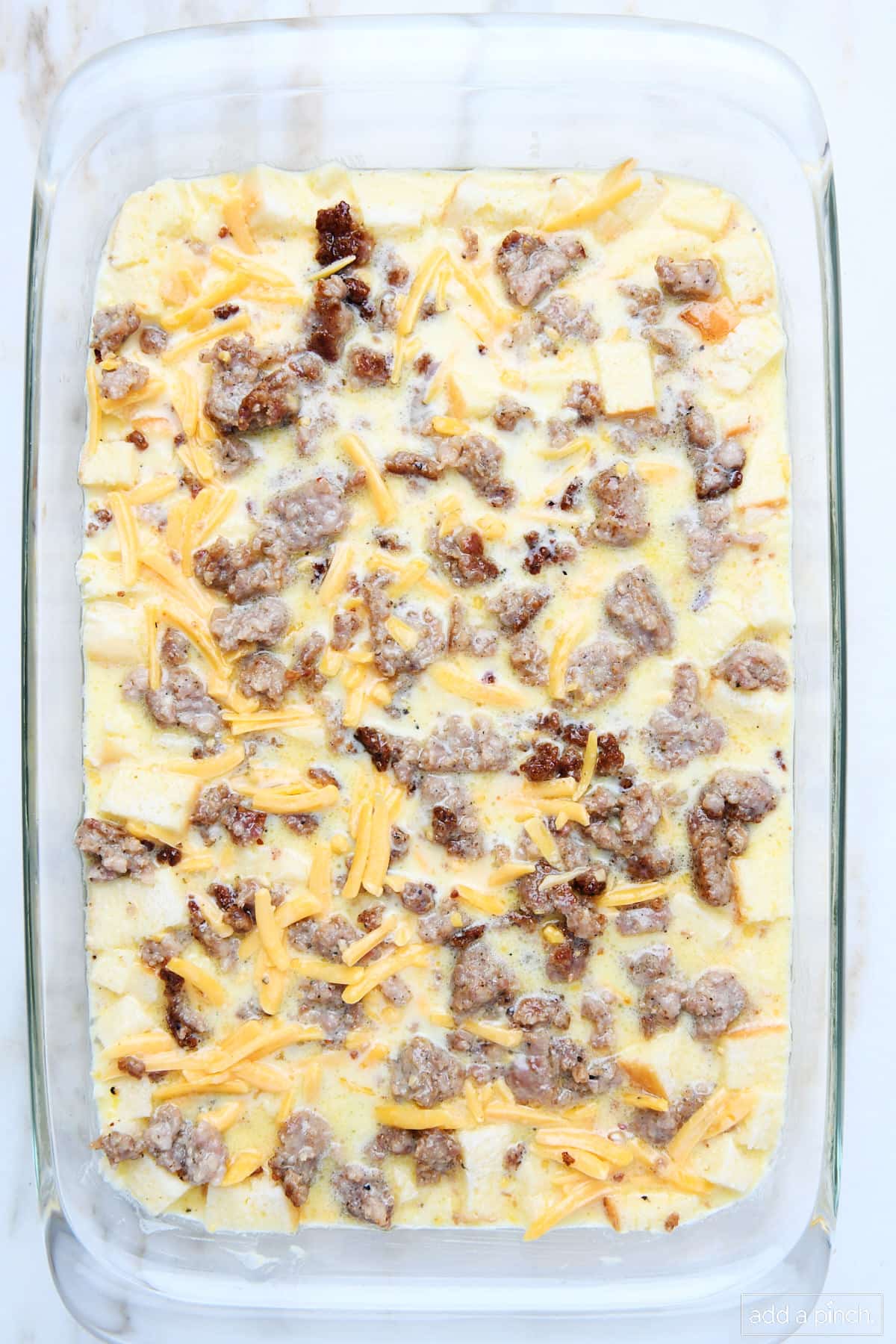 Unbaked breakfast casserole in a glass baking dish.