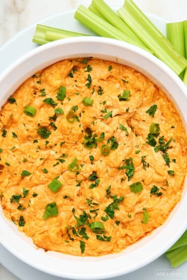 Baked dip topped with sliced onions and chopped parsley ready to be served.