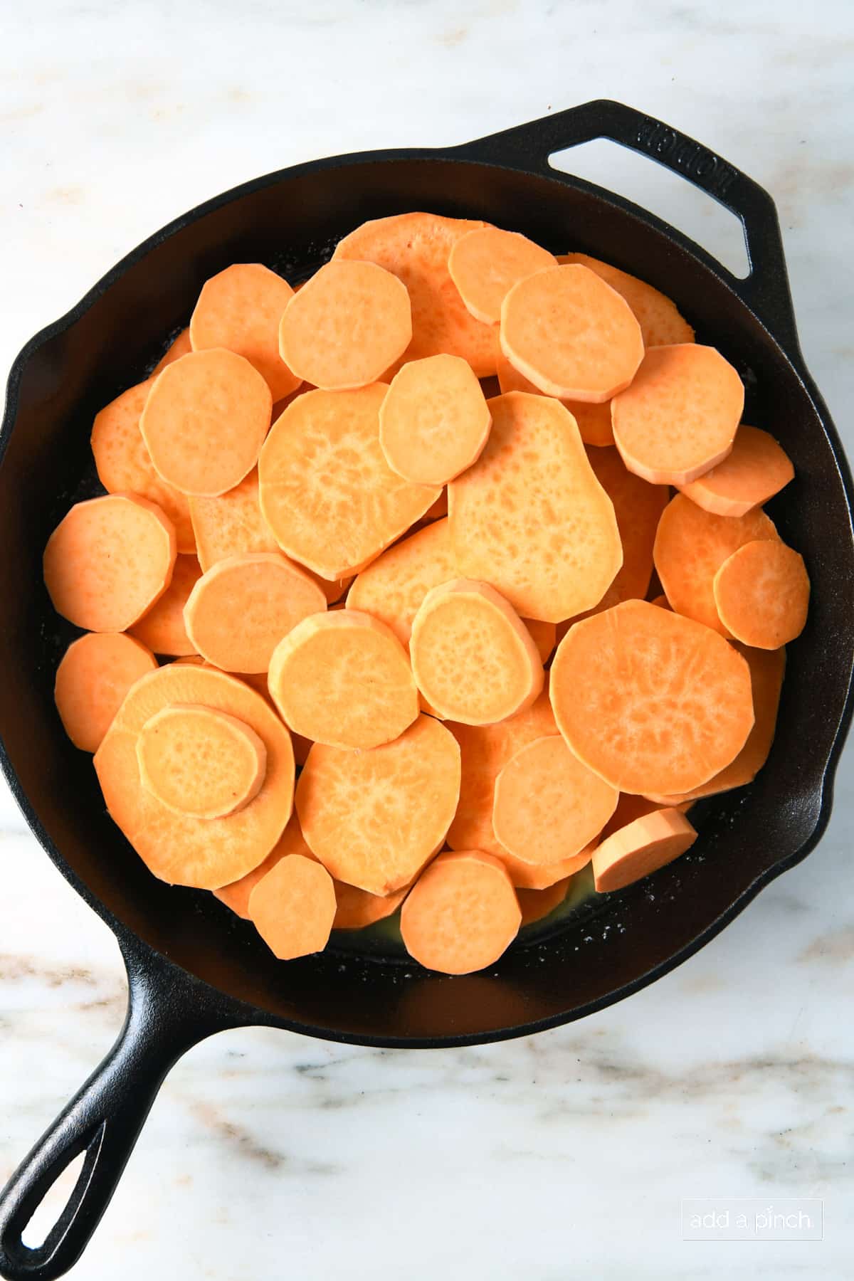 Sliced sweet potatoes in a skillet with melted butter.