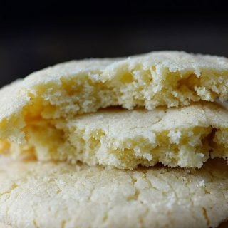 Photo of a stack of three sugar cookies on a dark background.