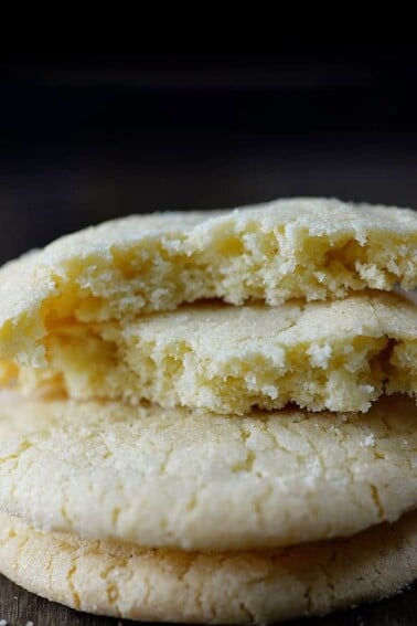 Photo of a stack of three sugar cookies on a dark background.