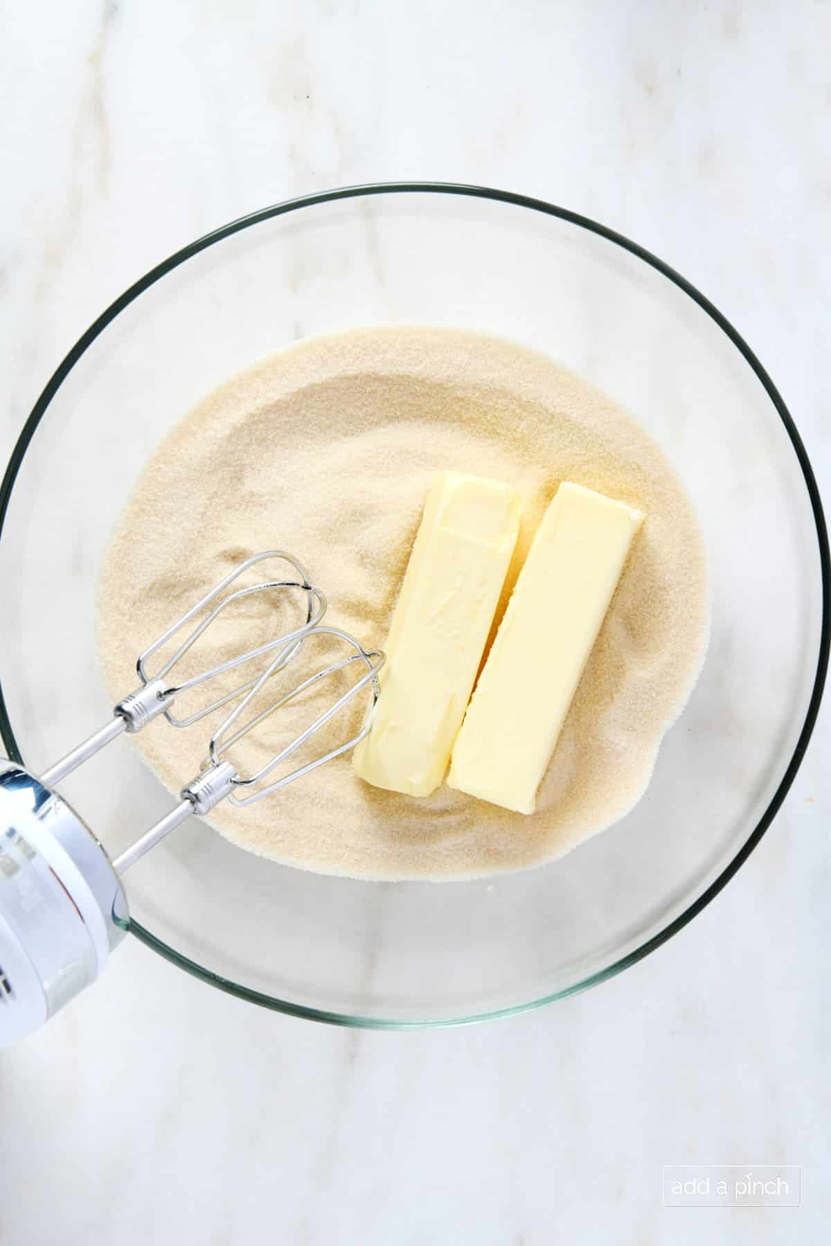 Butter and sugar in a glass mixing bowl with a hand mixer.