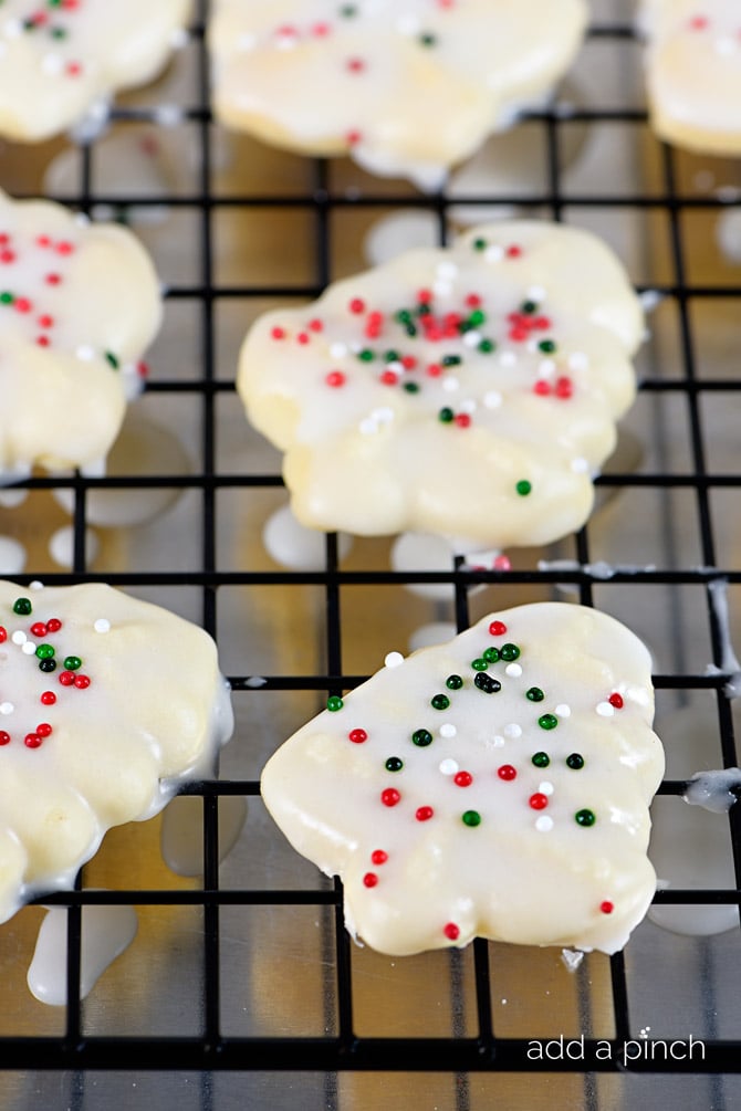 Cooling rack with freshly glazed Spritz cookies with sprinkles on top.