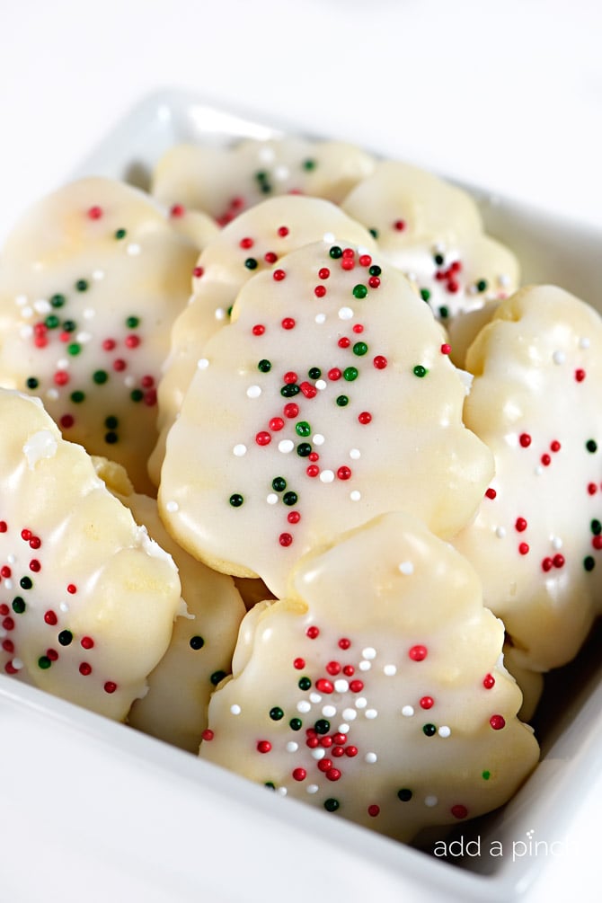 Stack of glazed Spritz cookies with red, green, and white sprinkles.