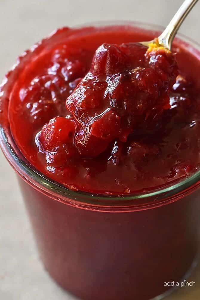 Homemade Cranberry Sauce recipe in a glass bowl with a silver spoon.