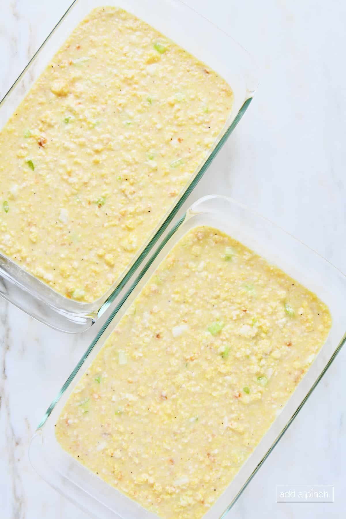 Cornbread dressing in two 9x13 baking dishes ready to be baked.