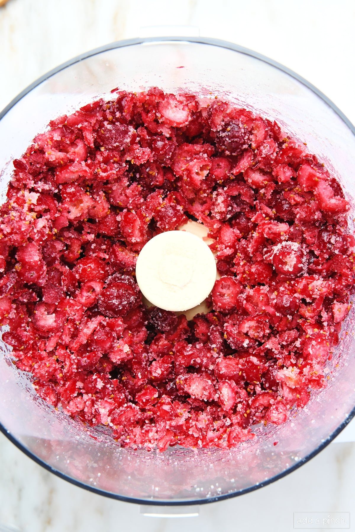 Cranberries are chopped and blended with sugar in the food processor.