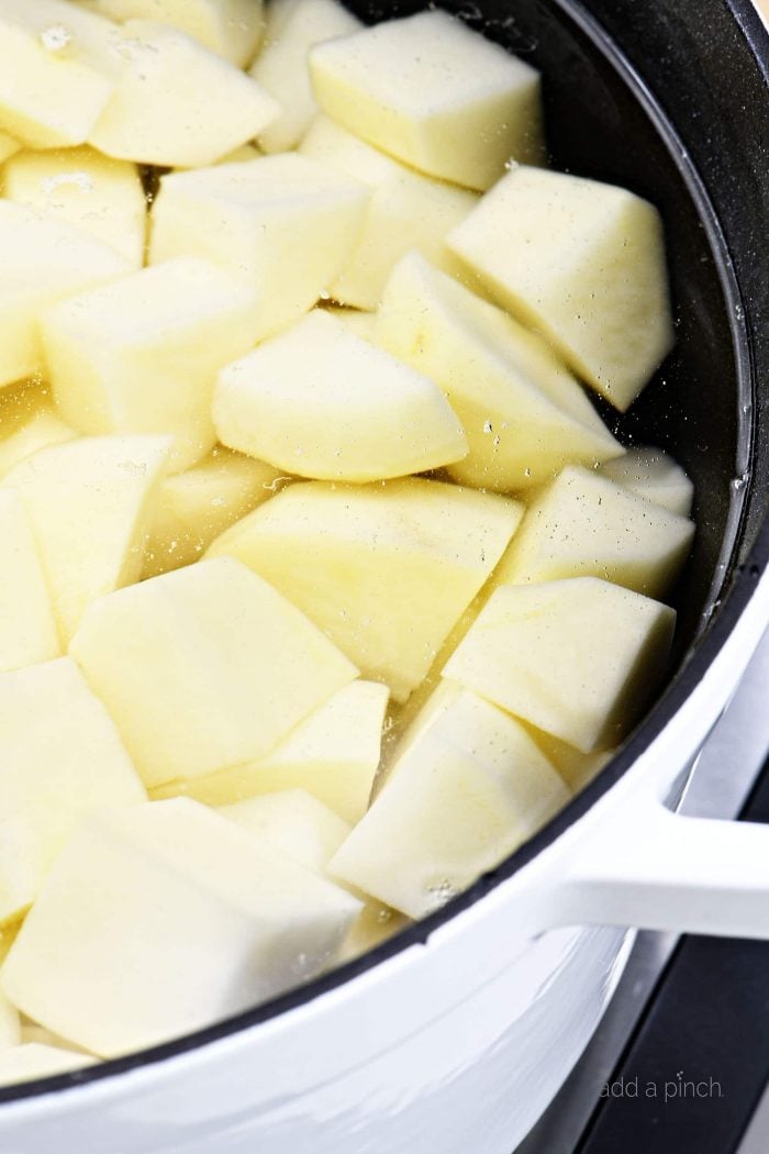 Image of potatoes in a Dutch oven covered with water. 