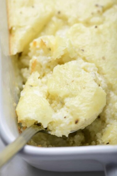 Photo of baked grits casserole in a baking dish on a marble surface.