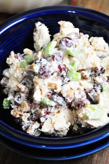 Photograph of chicken salad in a blue bowl on a dark counter.