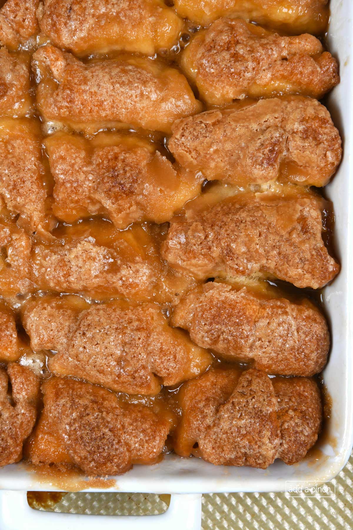 Photo of baked apple dumplings in a white baking dish on a baking sheet. 