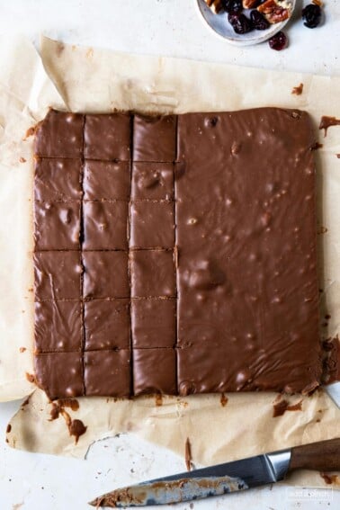 Photo of block of fudge being cut into individual pieces on a parchment