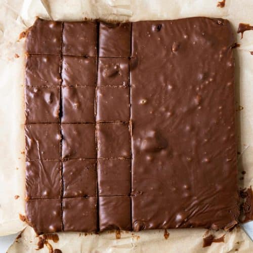 Photo of block of fudge being cut into individual pieces on a parchment