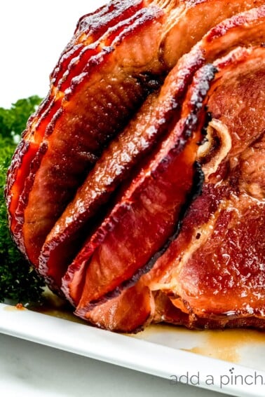 Photograph of cooked ham on a white platter.