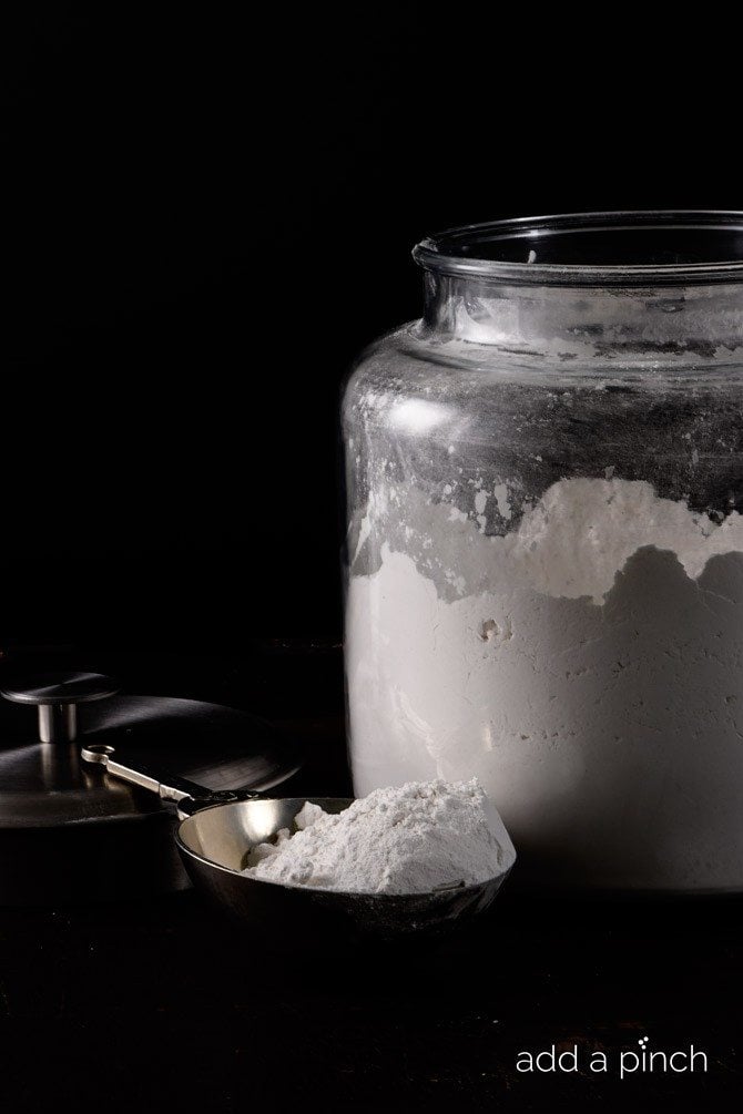 Flour in glass container with metal scoop // addapinch.com