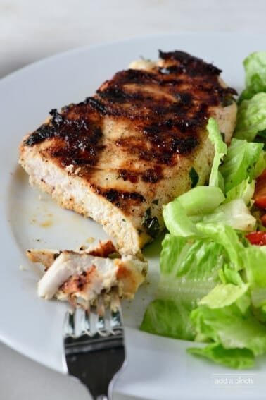 Grilled chicken on a white plate with a salad.