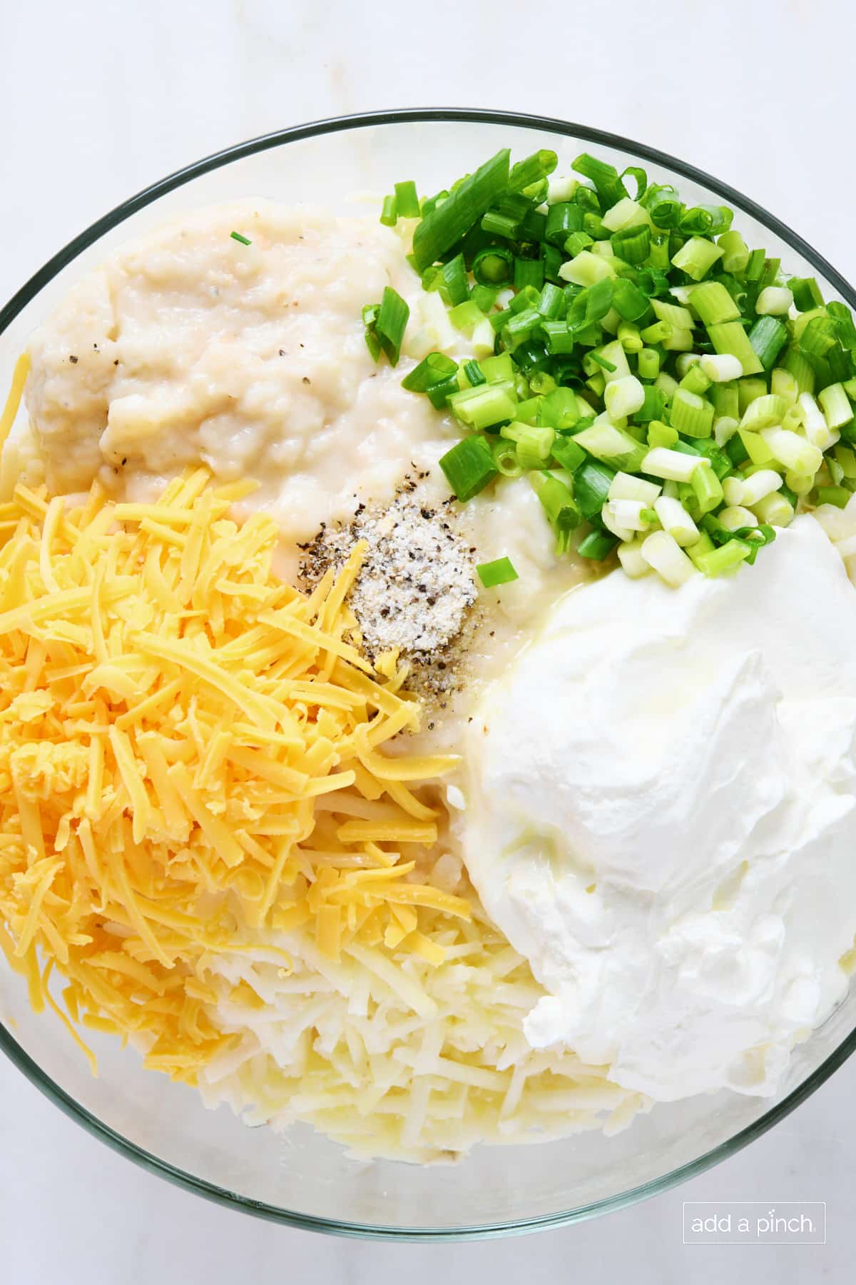 Ingredients for hashbrown casserole all added to a glass bowl to combine.