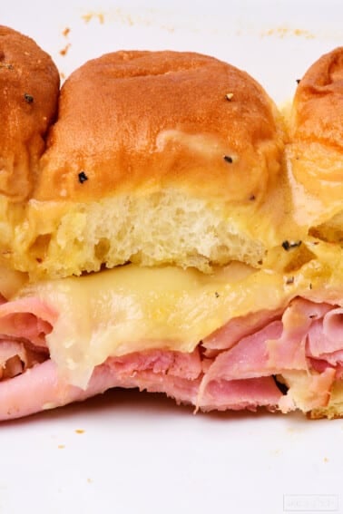 Ham and cheese sliders on a white plate.