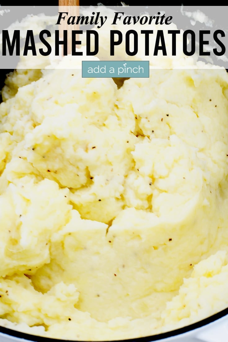 Buttery mashed potatoes in Dutch oven with wooden spoon.