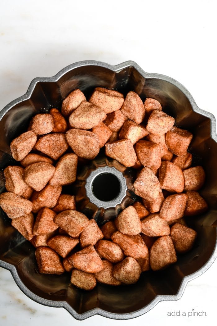 Photograph of monkey bread before it has been baked. Shown in a bundt pan on white marble. 