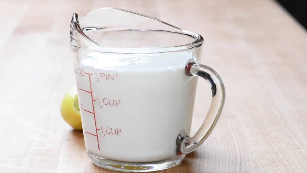 Cup of milk with a lemon next to it to make homemade buttermilk substitute.