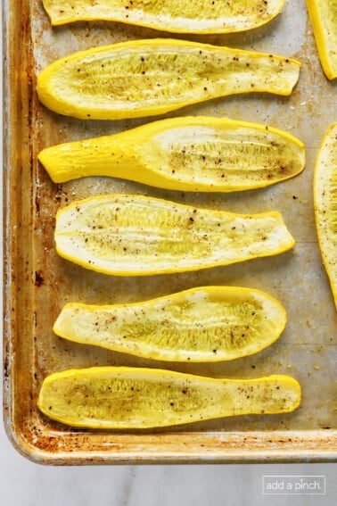 Roasted squash on a baking sheet on a marble surface.