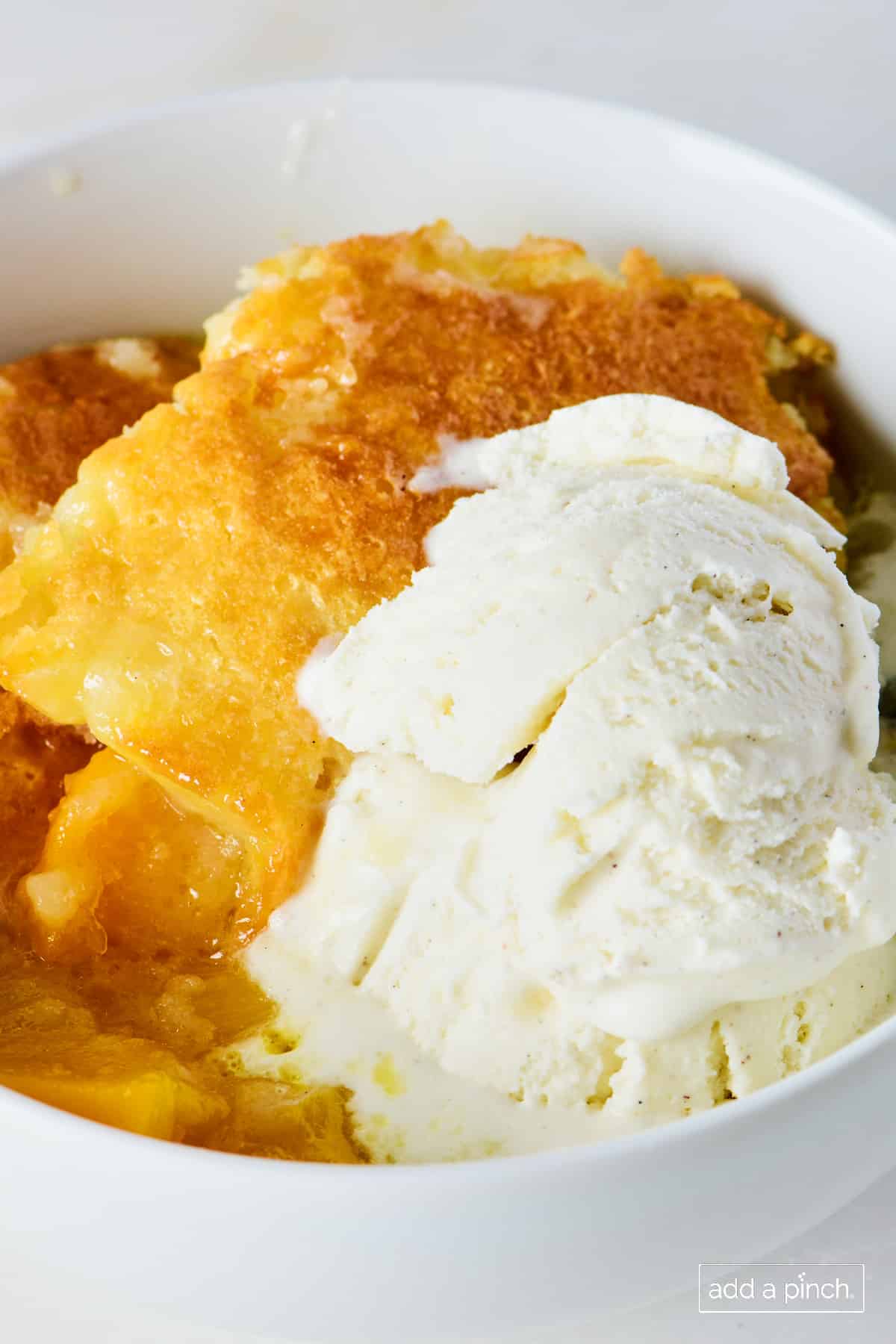 peach cobbler with ice cream in a white bowl