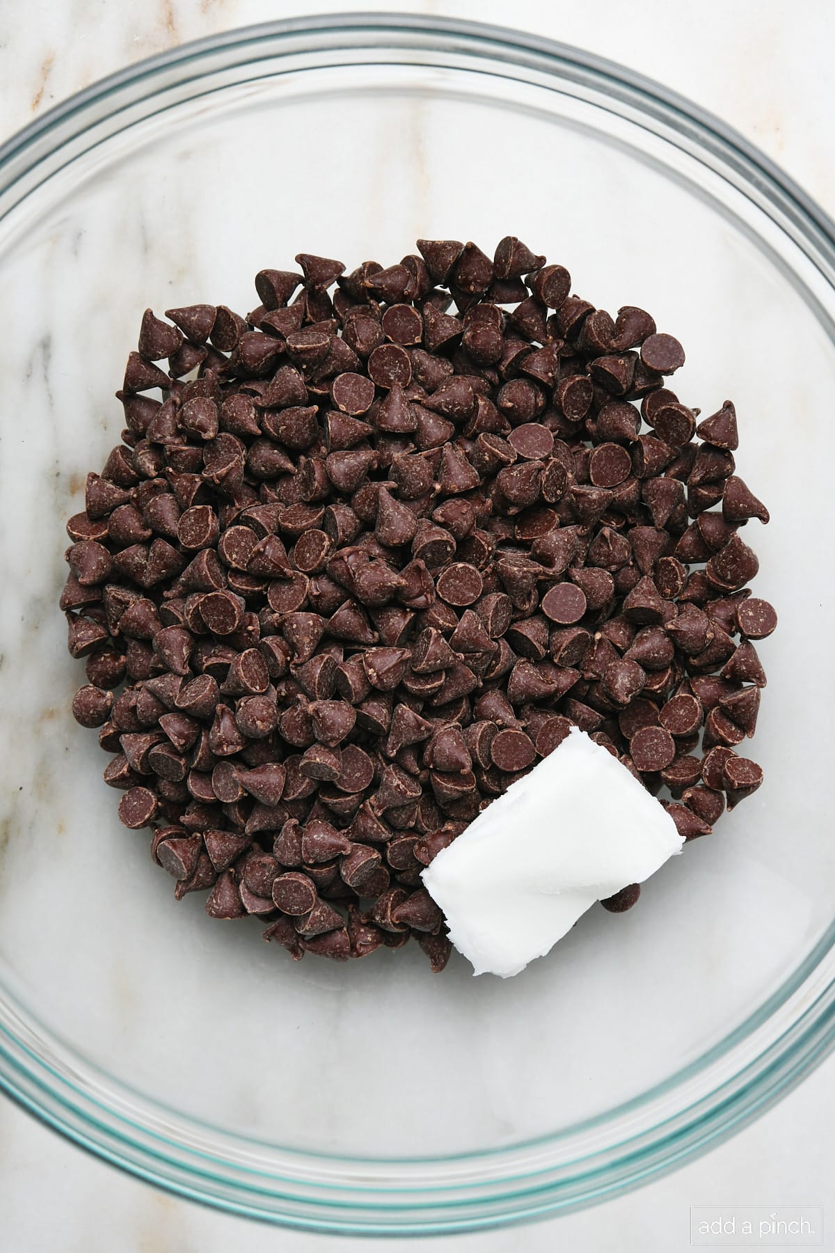 Chocolate chips and coconut oil in a glass mixing bowl.