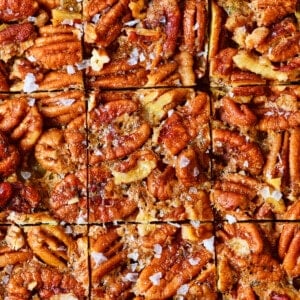 Pecan pie bars cut into individual squares sprinkled with flakey salt.