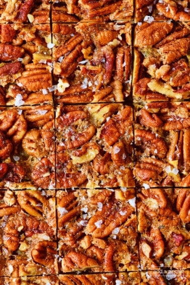 Pecan pie bars cut into individual squares sprinkled with flakey salt.