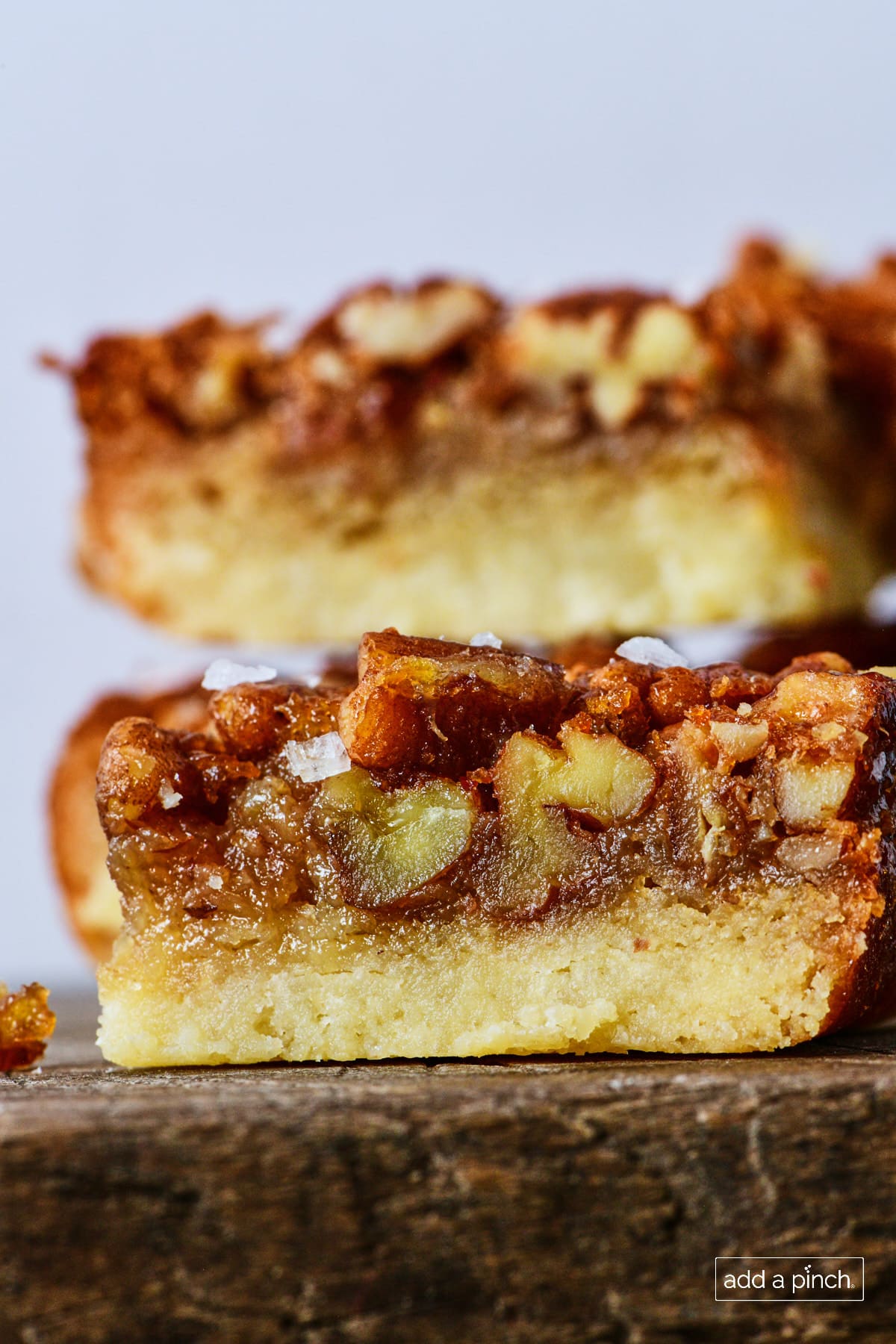 Stack of pecan pie bars on a wooden board.