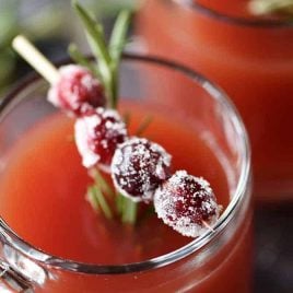 Cranberry Pomegranate Cider in glass cup with cranberry and rosemary garnish.