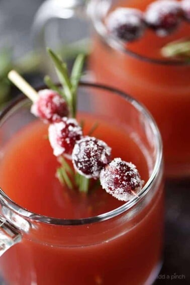 Cranberry Pomegranate Cider in glass cup with cranberry and rosemary garnish.