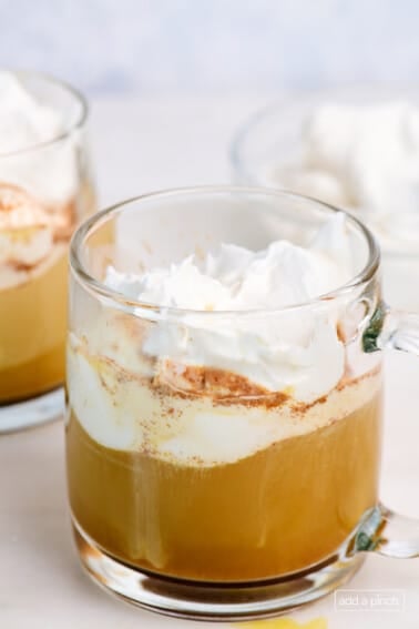 Glass mugs with hot pumpkin spice latte topped with whipped cream.