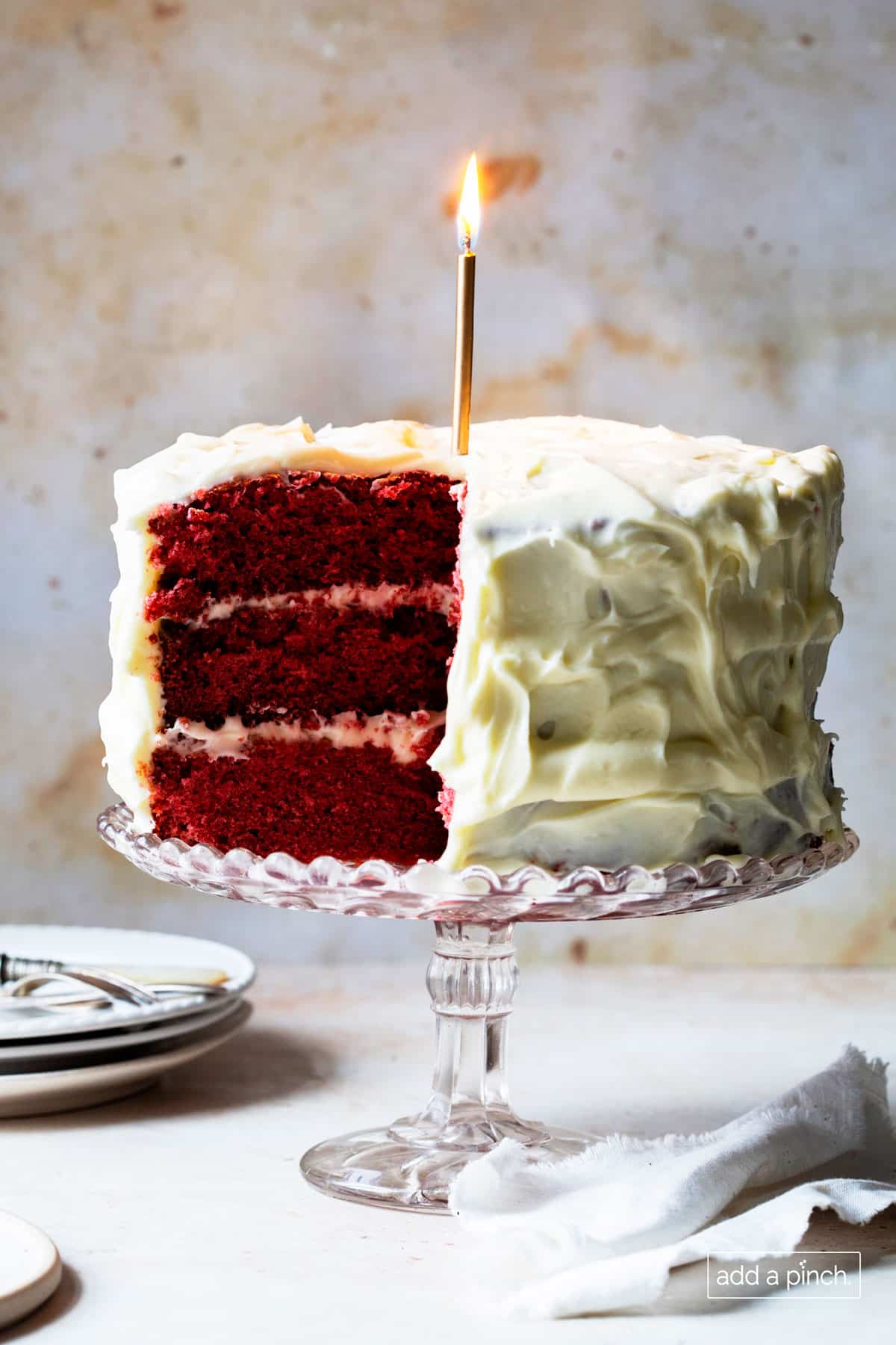 Image of red velvet cake with a lit gold candle.