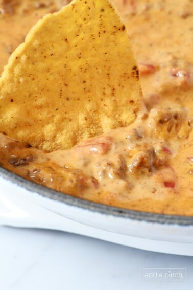 Creamy cheesy dip in a white dip with a tortilla chip.