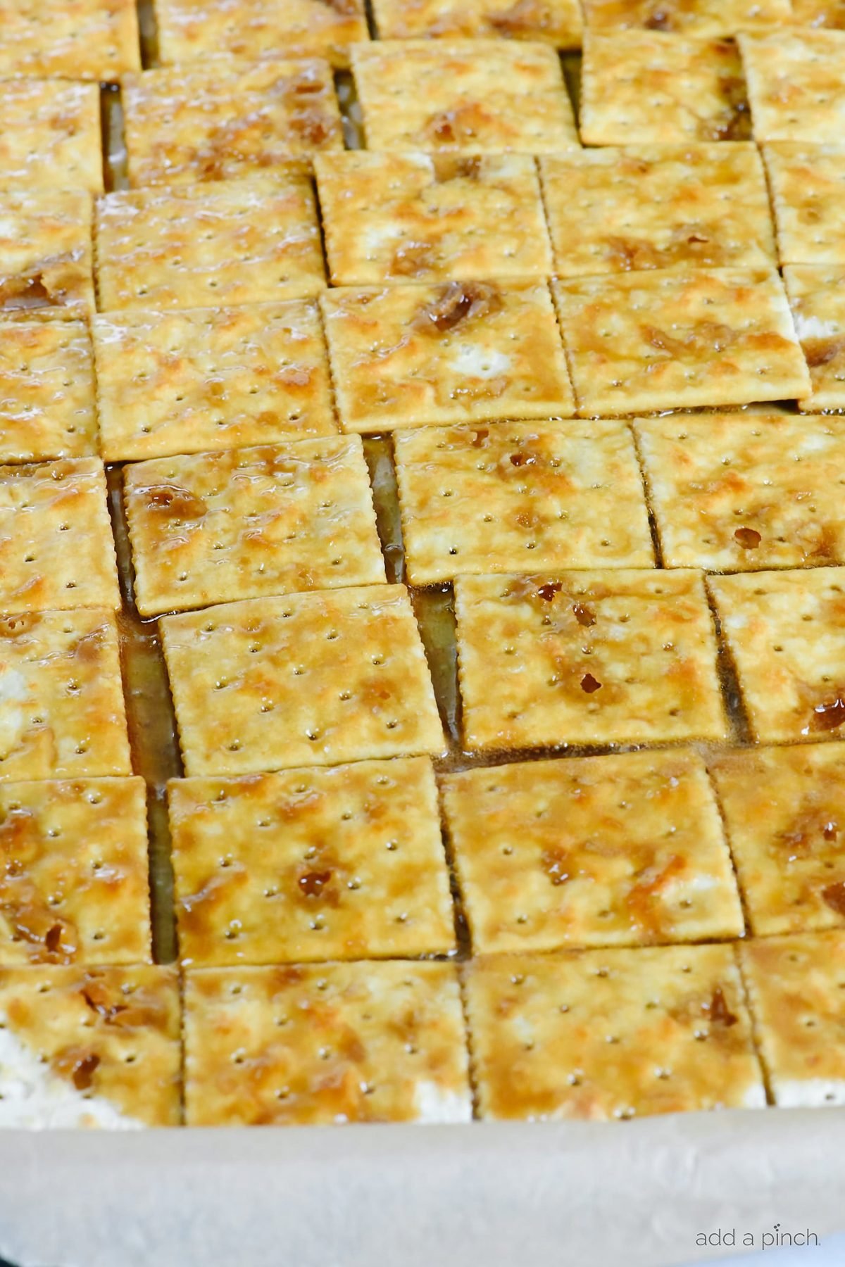 Saltine crackers on a baking sheet have caramel poured over them. 