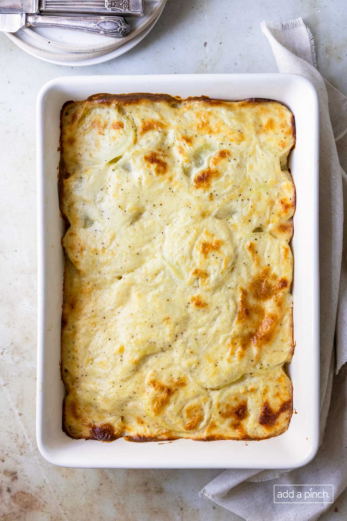 Baked scalloped potatoes in a white baking dish.