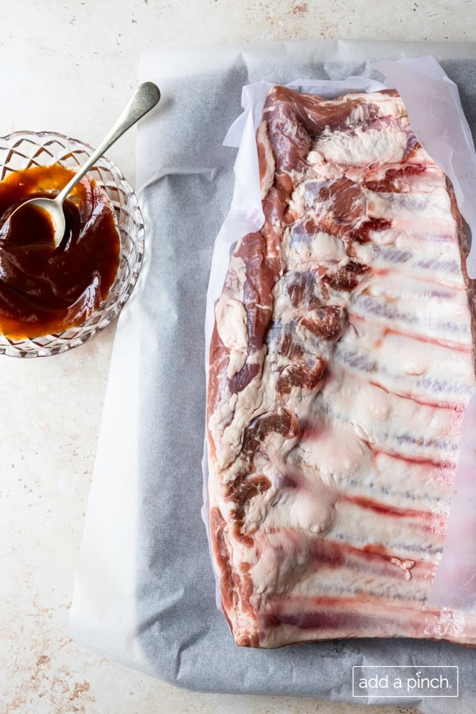 Photo of slab of ribs and bbq sauce ready to be cooked.