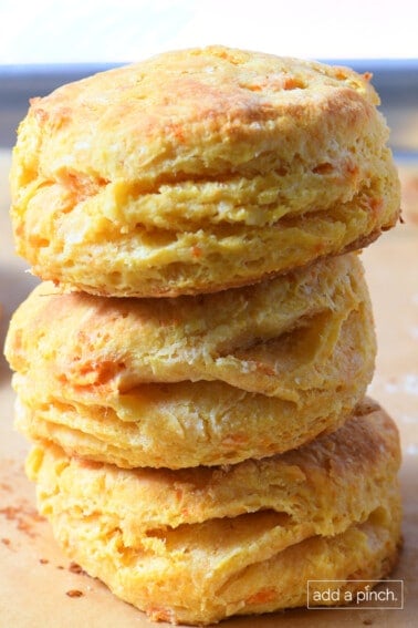 Three sweet potato biscuits stacked on a baking sheet lined with parchment paper.