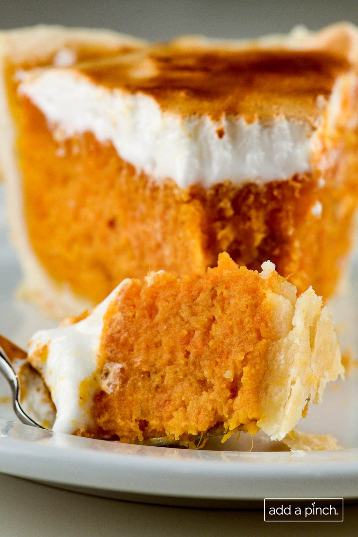 Closeup photograph of slice of sweet potato pie on a white plate. 