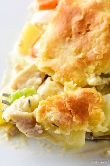 Slice of homemade turkey pot pie on a white plate with a fork.