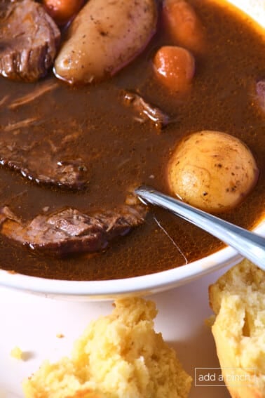 Bowl of venison stew served with cornbread muffins.