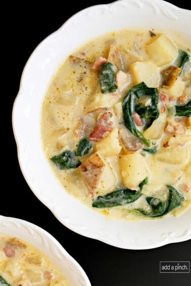 Photo of Zuppa Toscana soup in a white bowl on a black countertop.